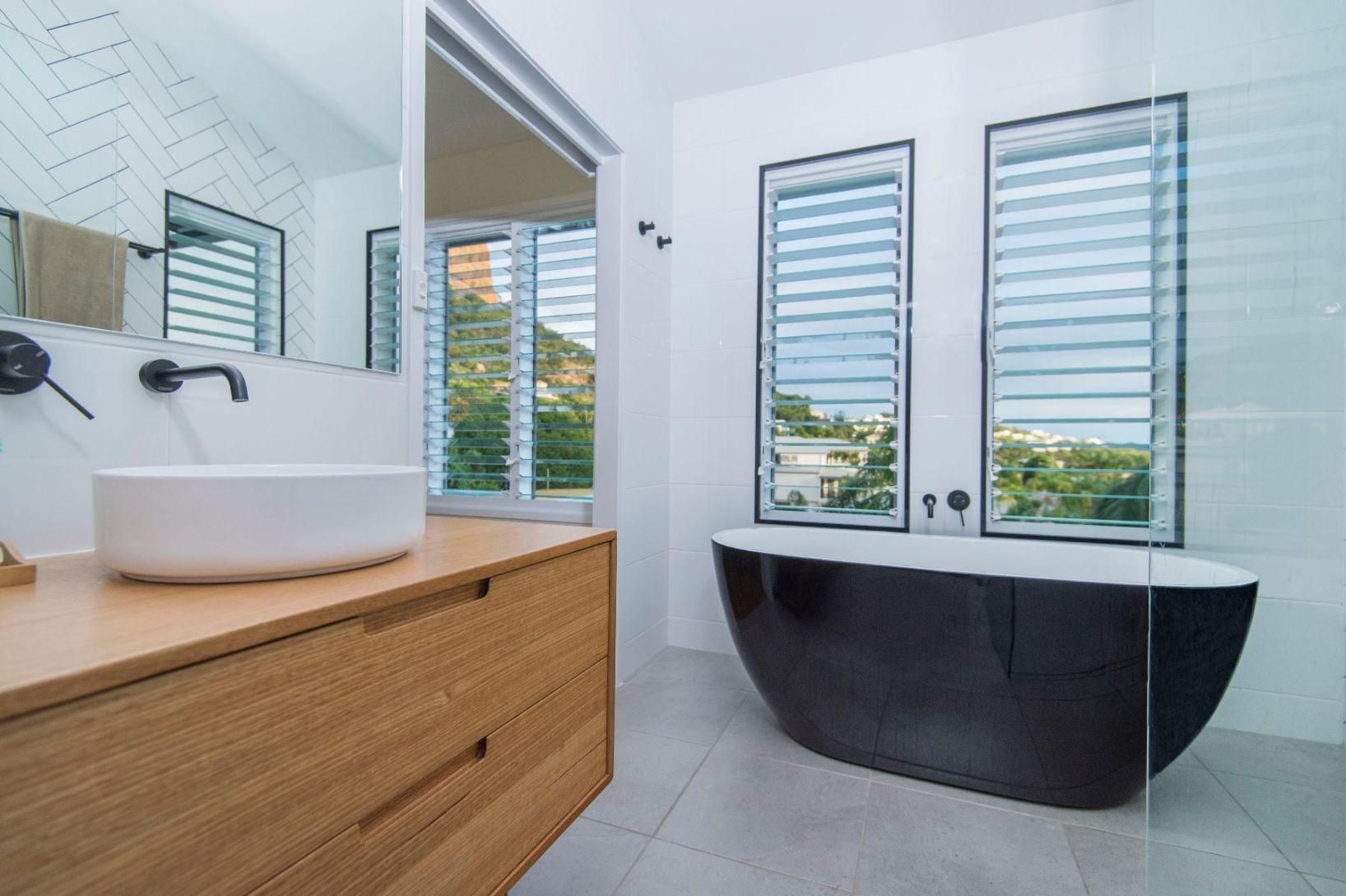 A Bathroom With a Black Tub , Sink and Mirror — Pro-Jax Pty Ltd in Bohle, QLD