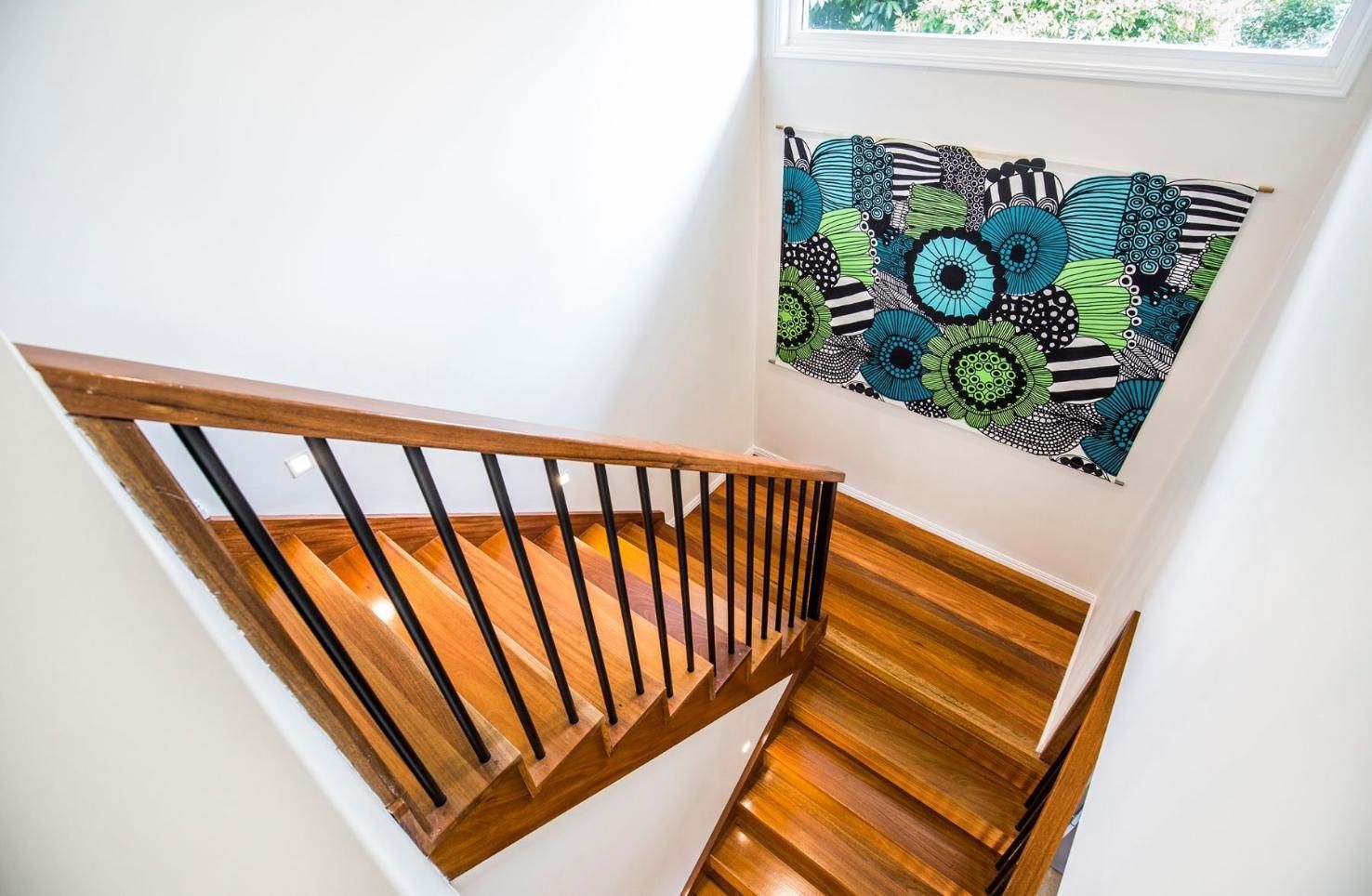 A Wooden Staircase With a Black Railing and a Painting on the Wall — Pro-Jax Pty Ltd in Bohle, QLD