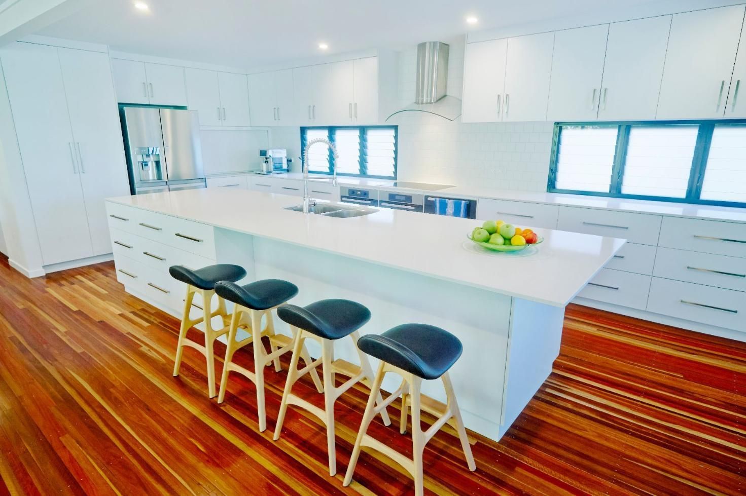 A Kitchen With a Large Island and Stools — Pro-Jax Pty Ltd in Bohle, QLD
