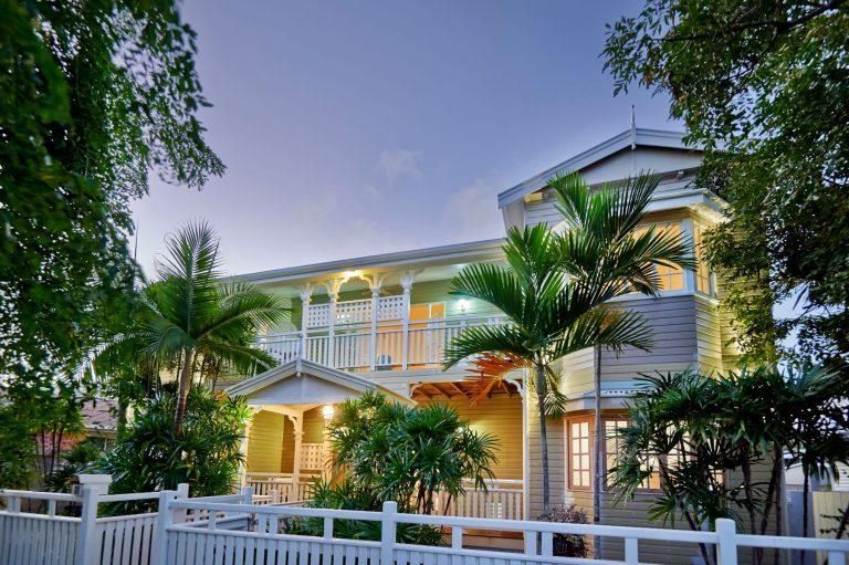 A Large House With a White Fence and Palm Trees in Front of It — Pro-Jax Pty Ltd in Bohle, QLD
