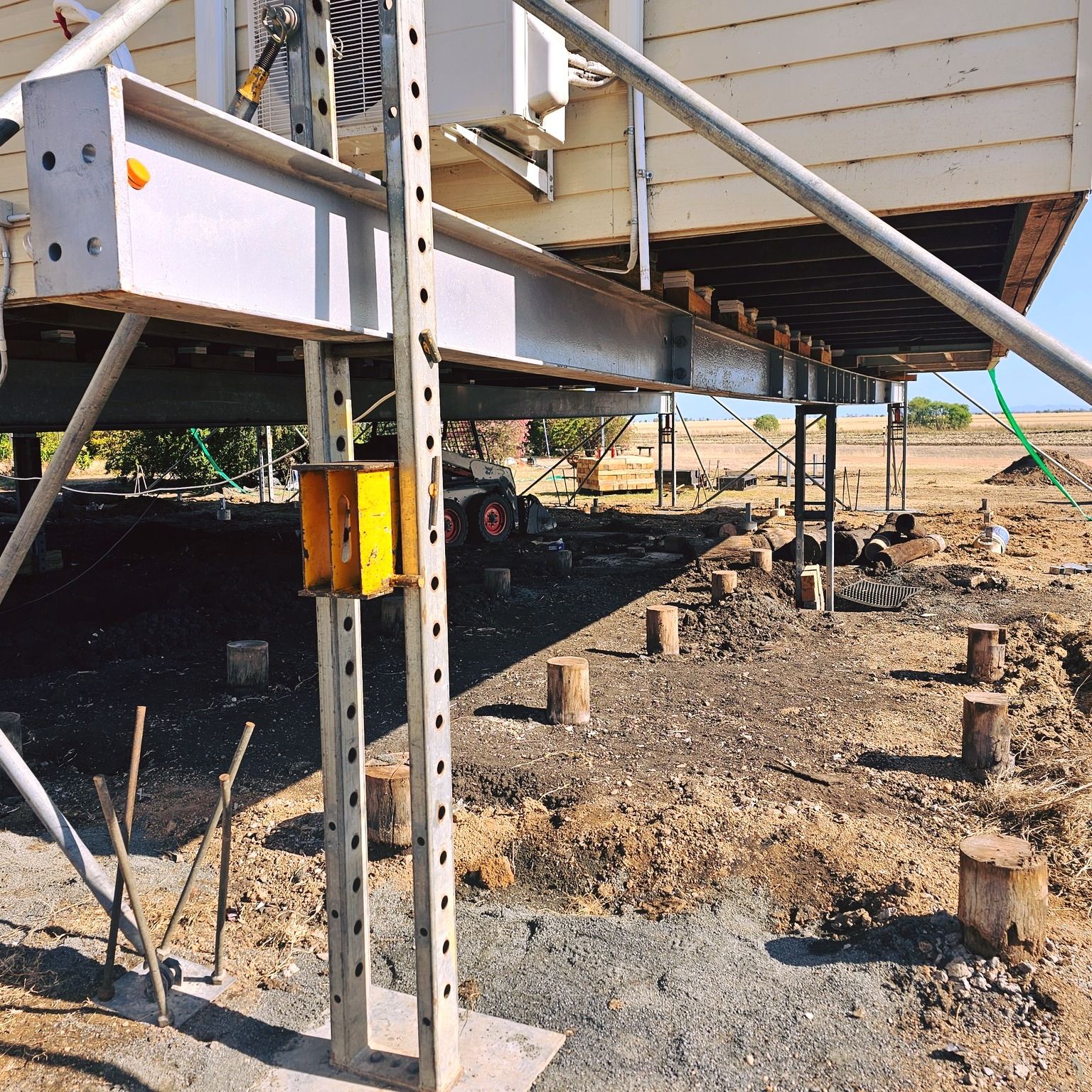 A house is being built on stilts in the dirt — Pro-Jax Pty Ltd in Bohle, QLD