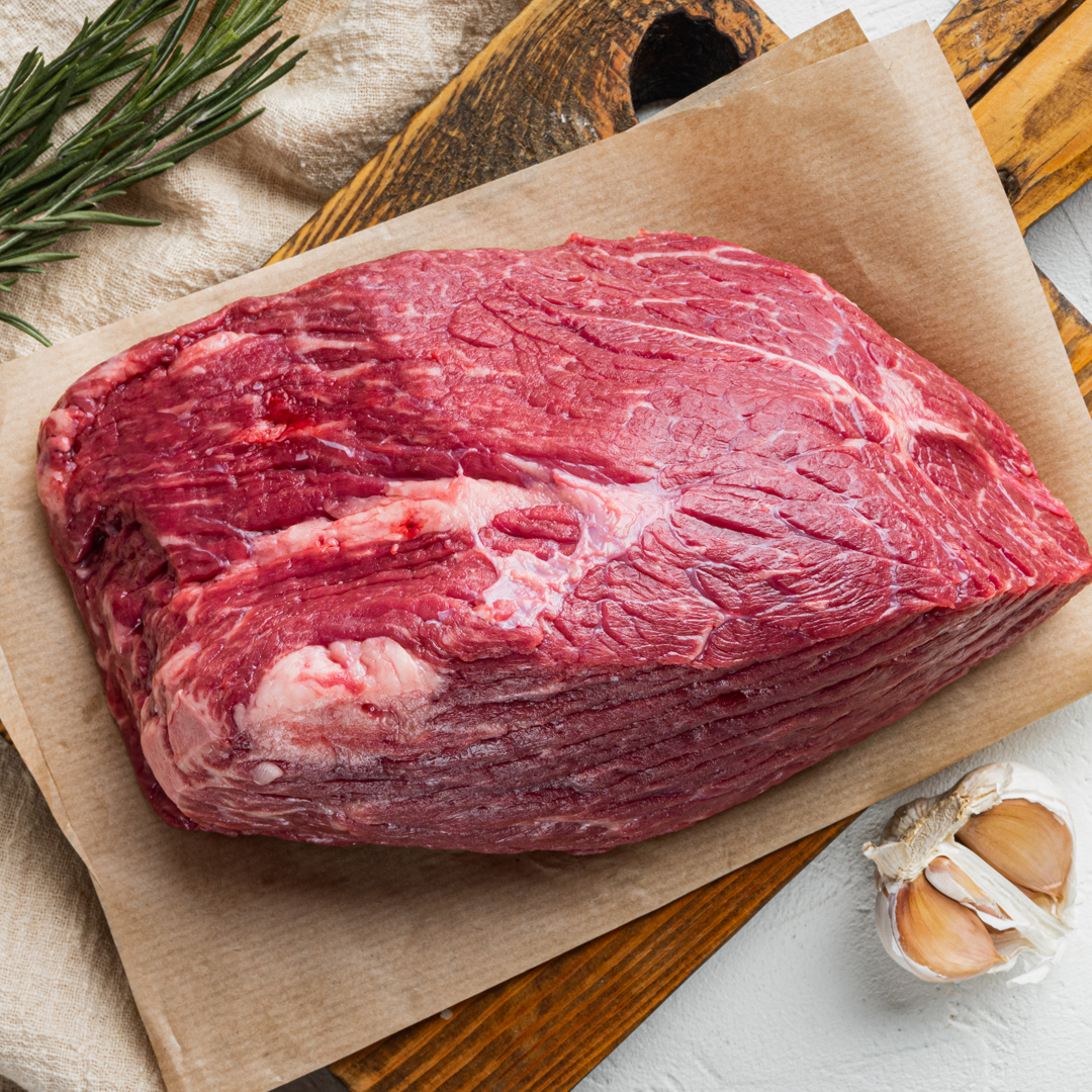 A piece of raw beef is sitting on a piece of brown paper.