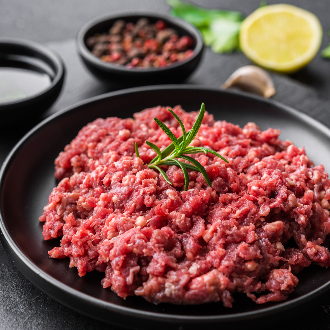 A black plate topped with ground beef and a sprig of rosemary.