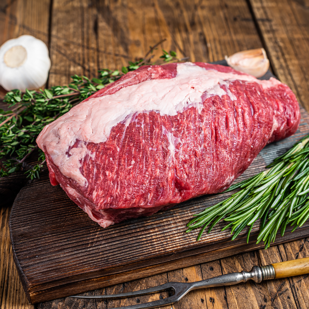 A piece of raw beef is sitting on a wooden cutting board.