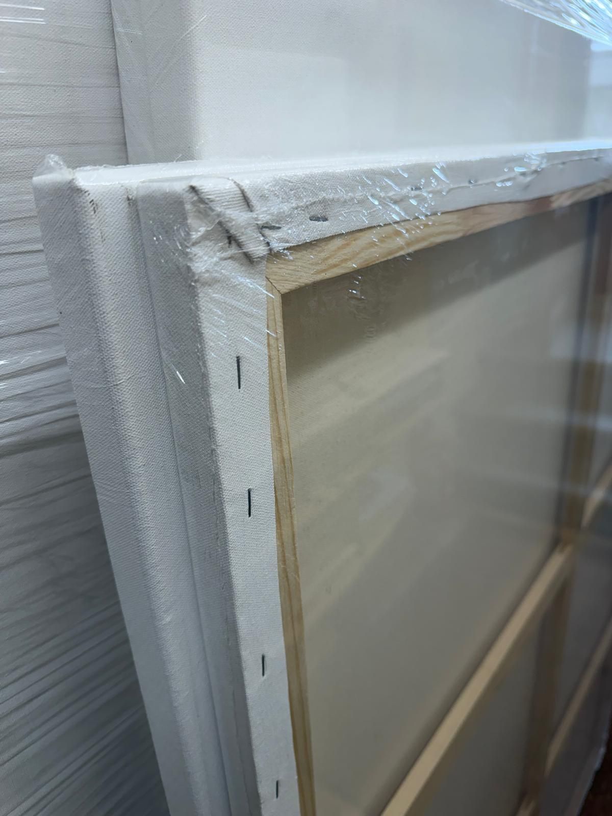 Wrapped framed panel leaning against a wall with white tape and plastic covering