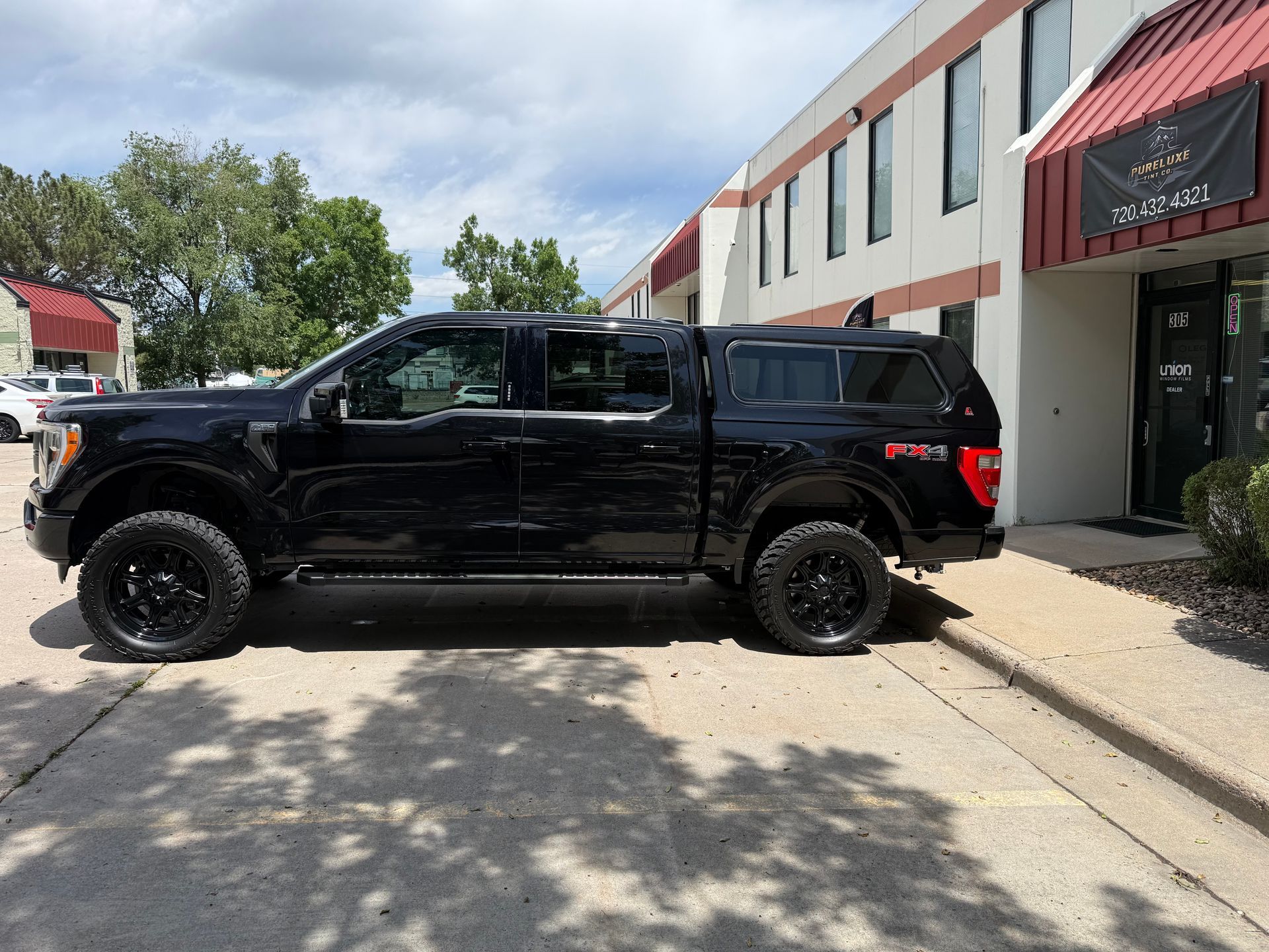 Black pickup truck parked outside a modern building on a sunny day