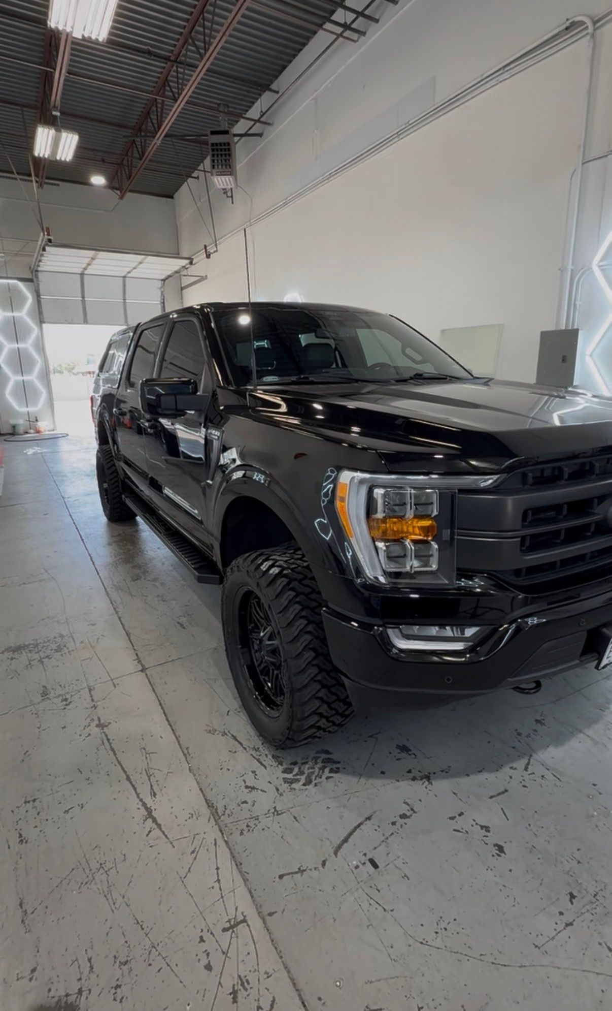 Black pickup truck parked inside a bright auto shop garage