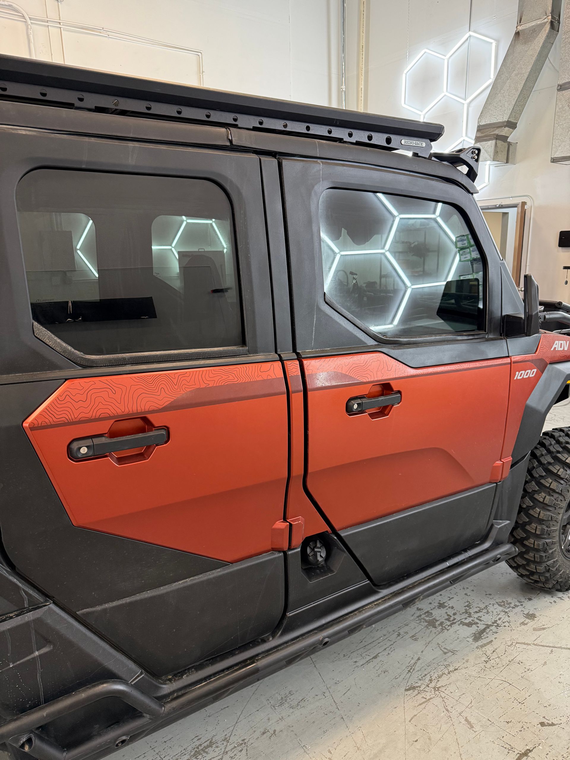 Orange and black off-road vehicle with hexagon-lit windows parked indoors
