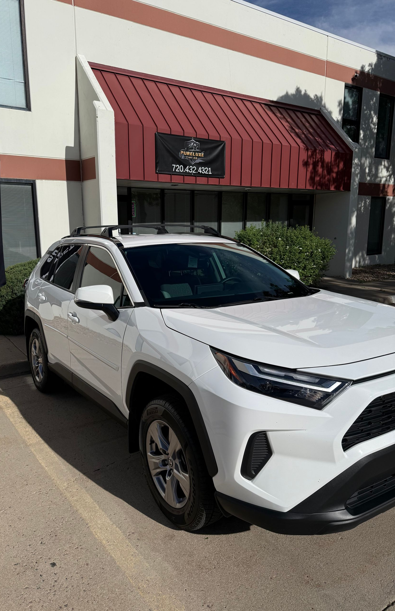 White SUV parked outside a storefront with a red awning and signage