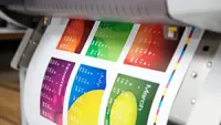 A printer printing a colorful calendar with months displayed, highlighting vibrant hues.