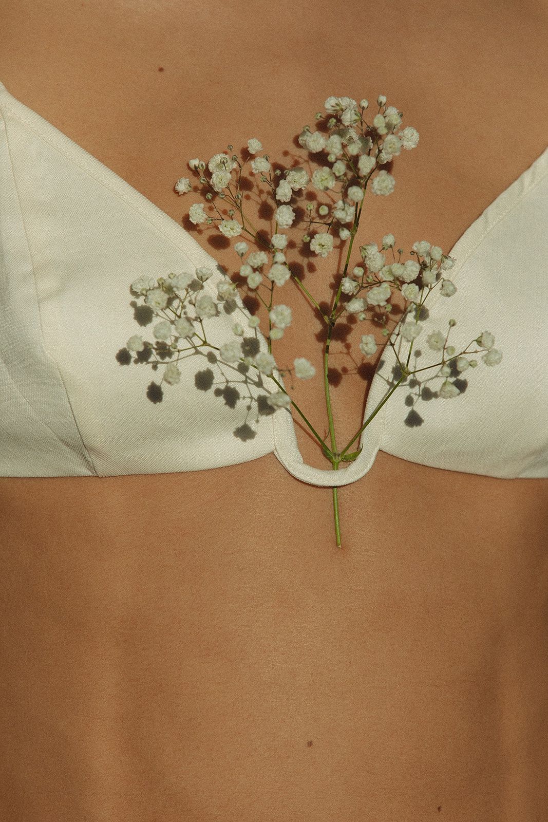 A woman is wearing a white bra with baby 's breath flowers on her chest.