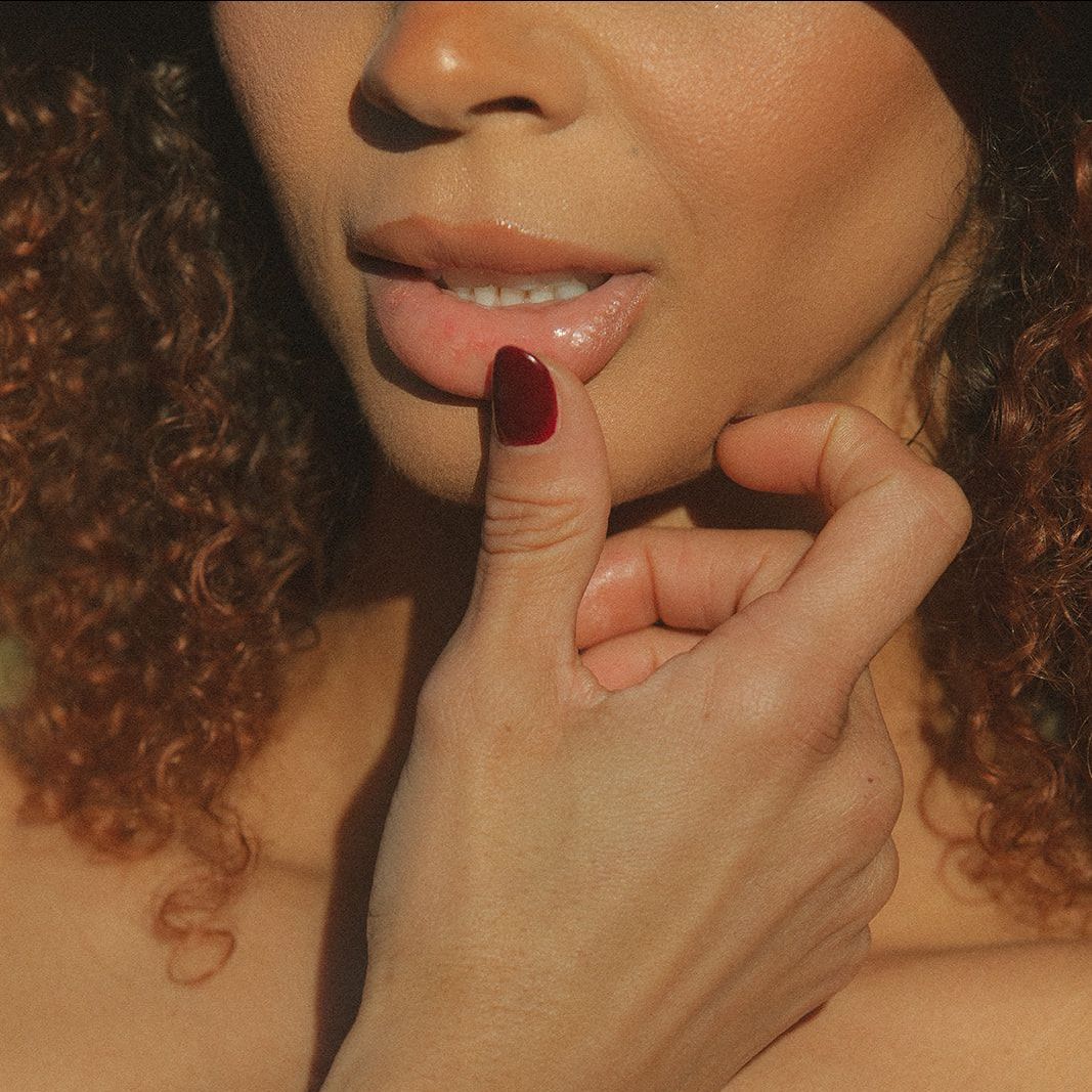 A close up of a woman 's face with her fingers on her lips.