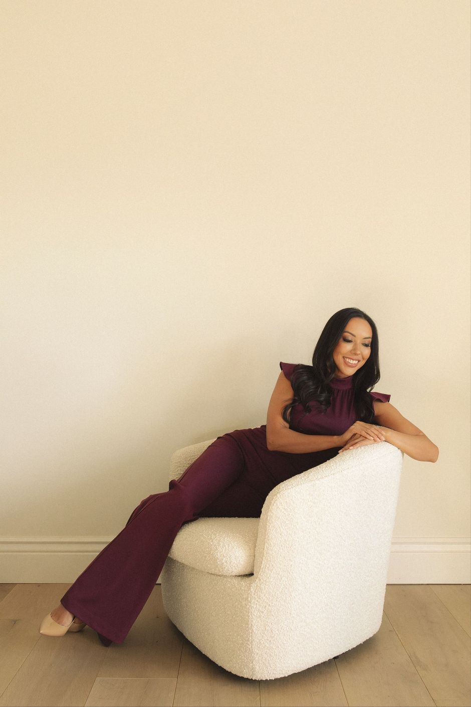 A woman in a purple jumpsuit is sitting in a white chair.