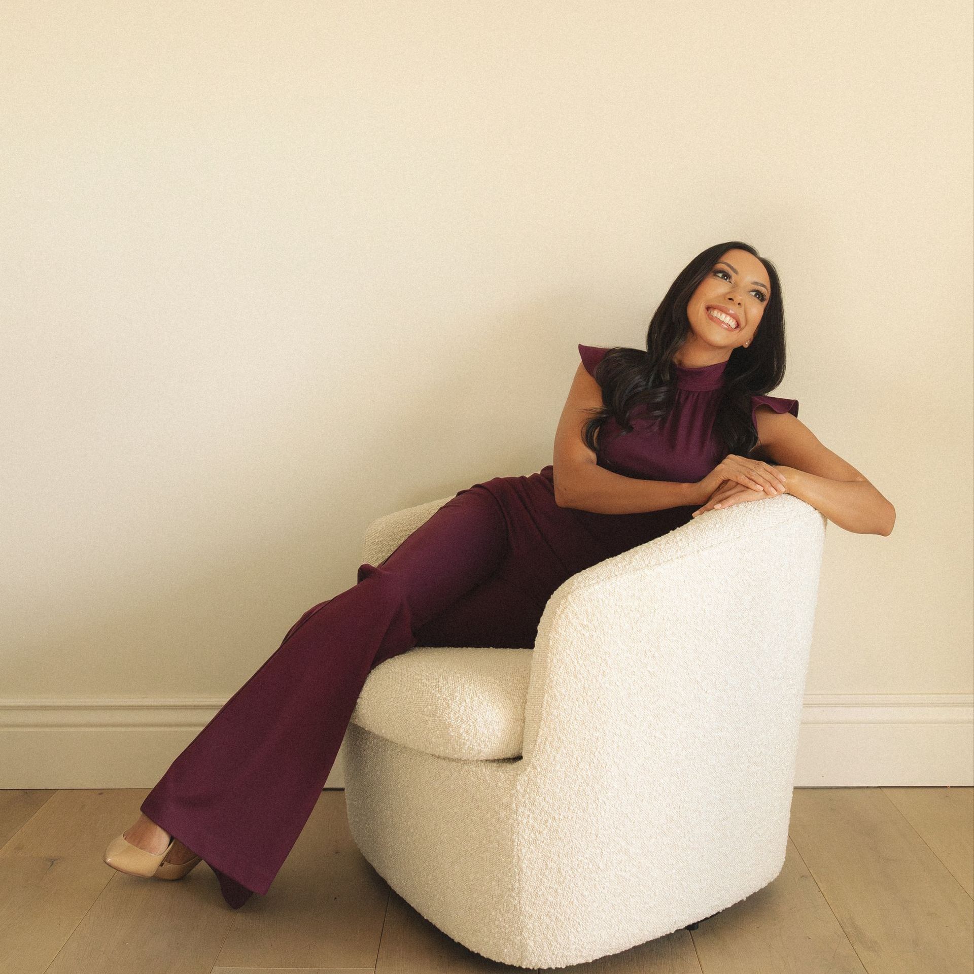 A woman in a purple jumpsuit is sitting in a white chair