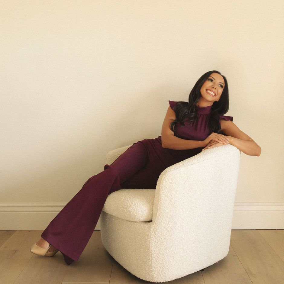 A woman in a purple jumpsuit is sitting in a white chair