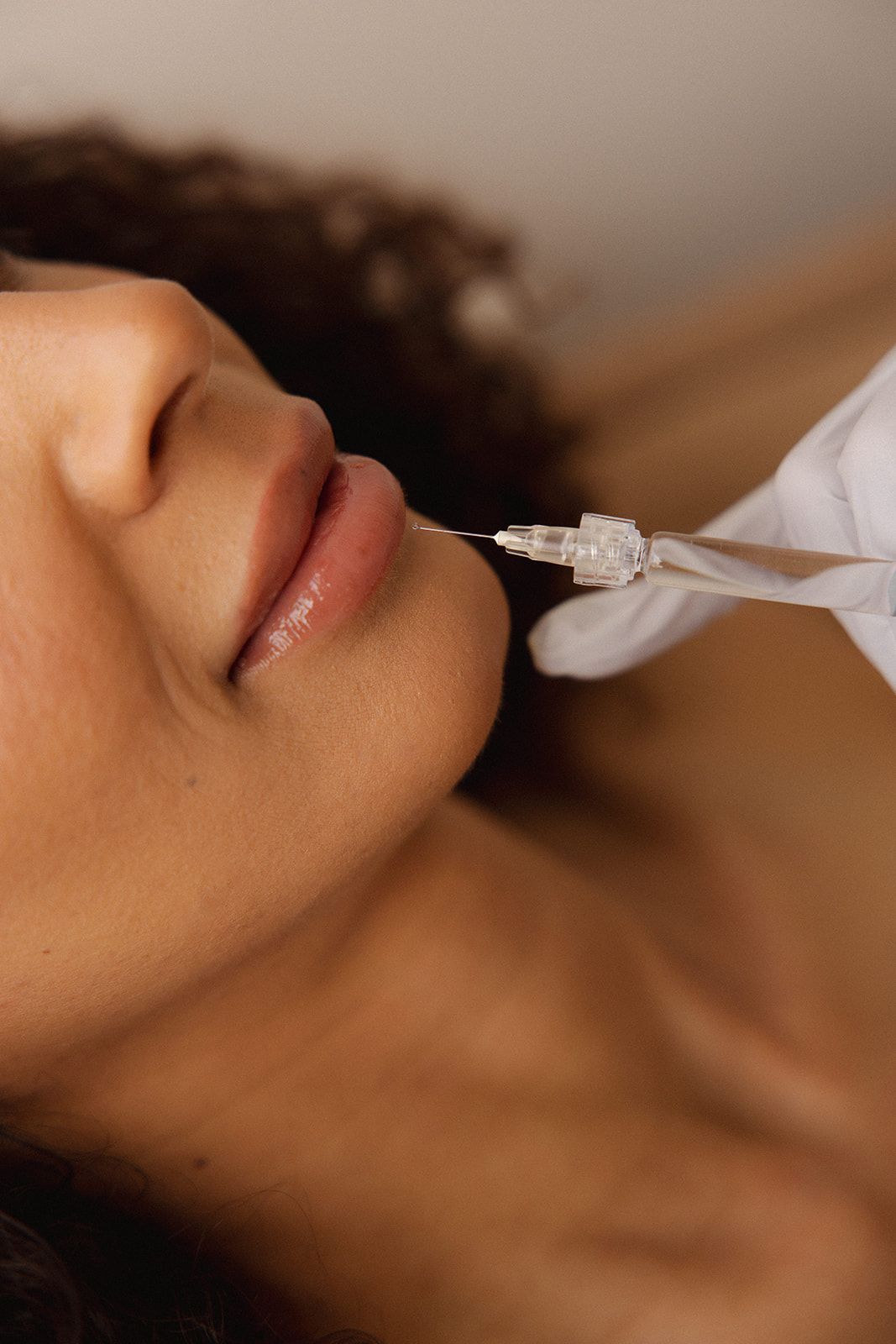 Close-up of a person receiving a lip injection with a syringe in a clinical setting