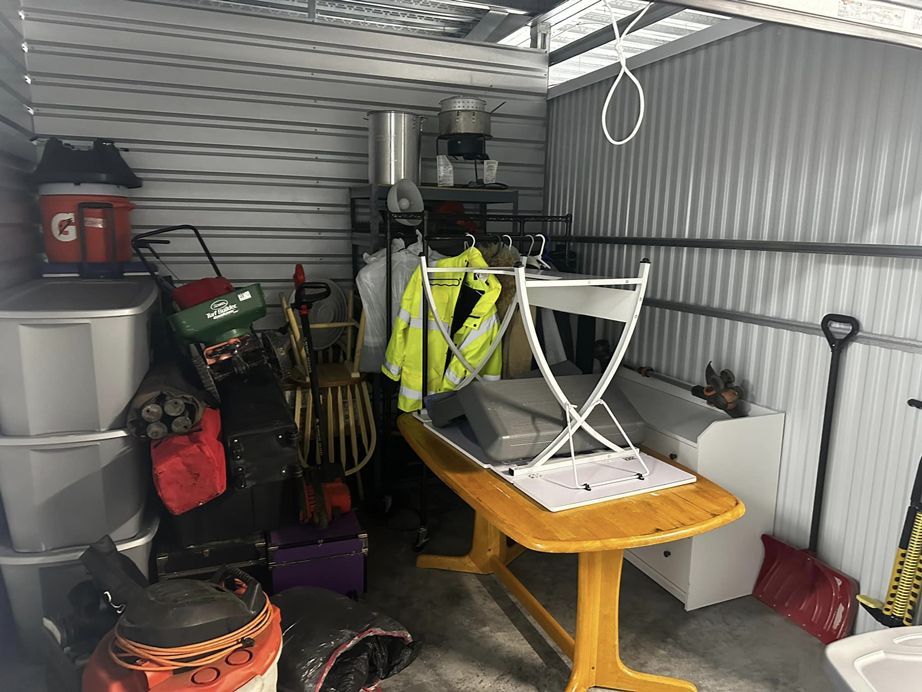 storage unit full of furniture, plastic bins , shop vac, and other items