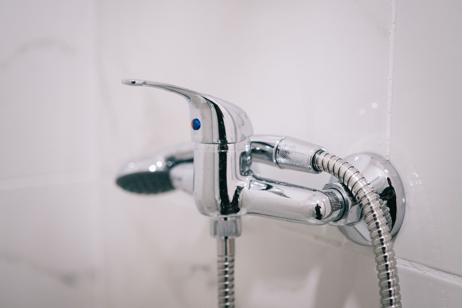 Plumber working on a silver water heater with a wrench in a utility room