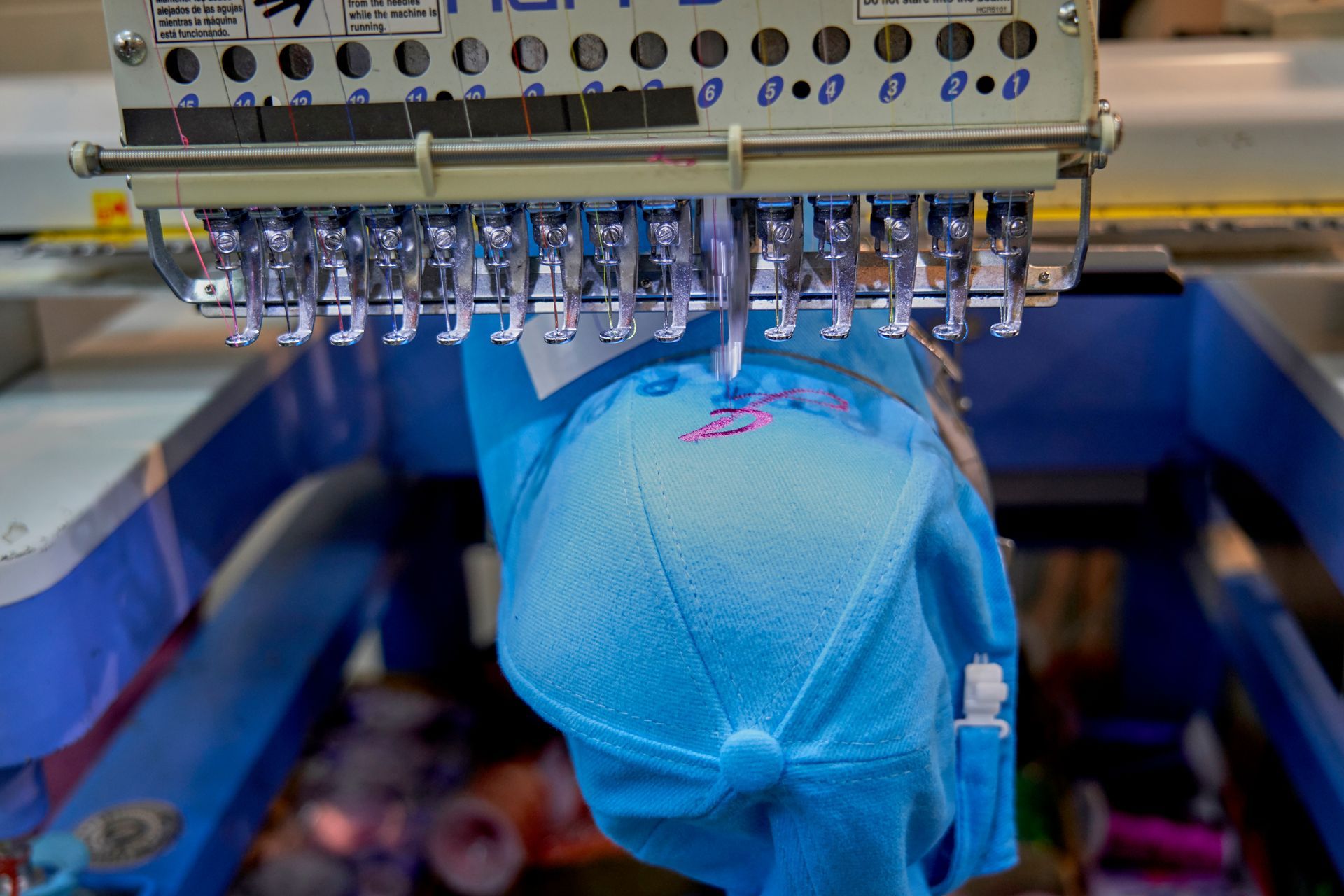 Blue cap under industrial embroidery machine stitching fabric