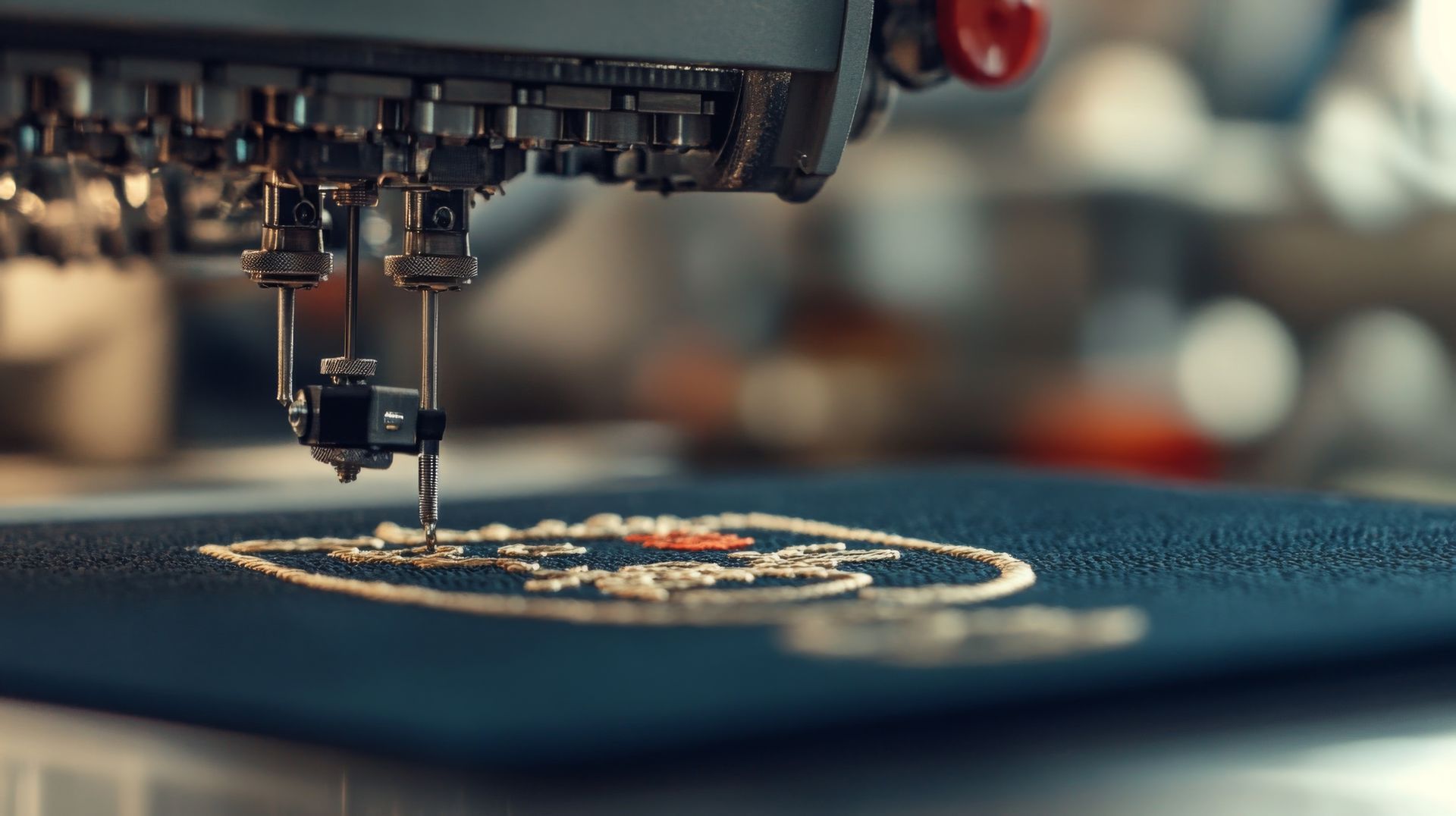 Close-up of an embroidery machine stitching a white design on dark fabric.