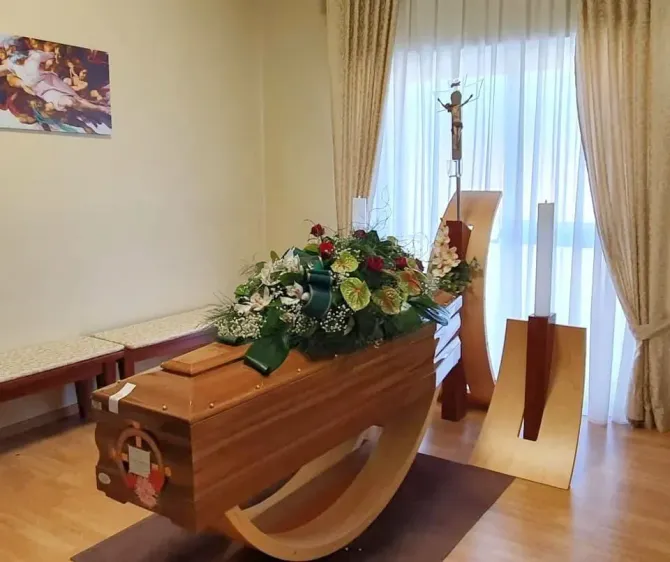 Bara di legno con composizione floreale in una cappella accanto a una finestra luminosa e tende