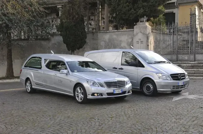 Due Mercedes color argento parcheggiate su una strada acciottolata, accanto a un muro di pietra.