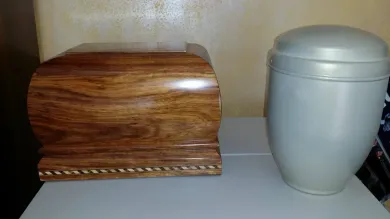 Scatola di legno e urna grigia su un tavolo contro una parete spoglia