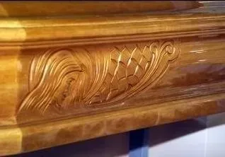 Primo piano di un pannello in legno intagliato e lucidato con decorazioni a foglie e volute.