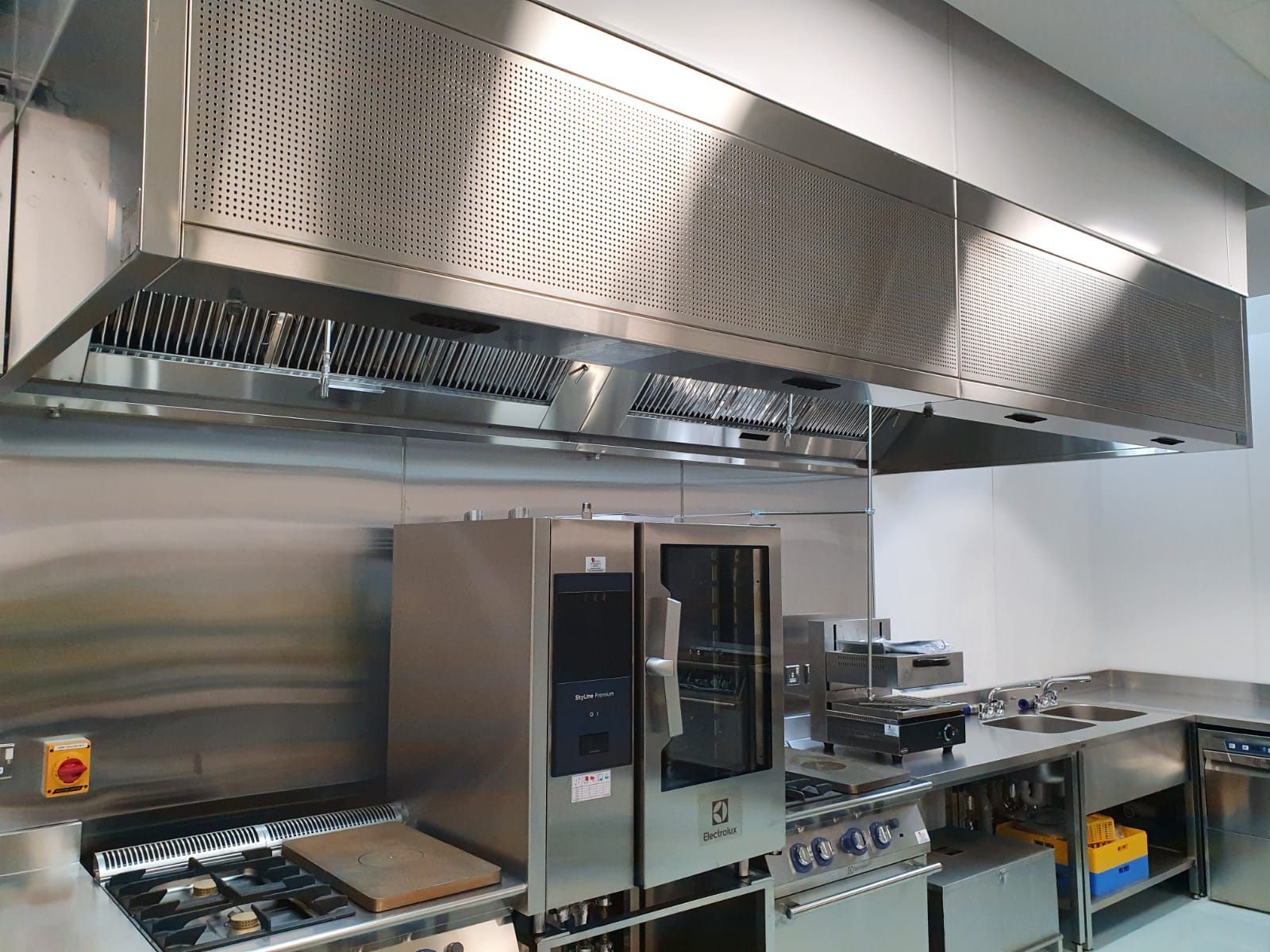Commercial kitchen with stainless steel appliances, stovetop, ovens, and large ventilation hood