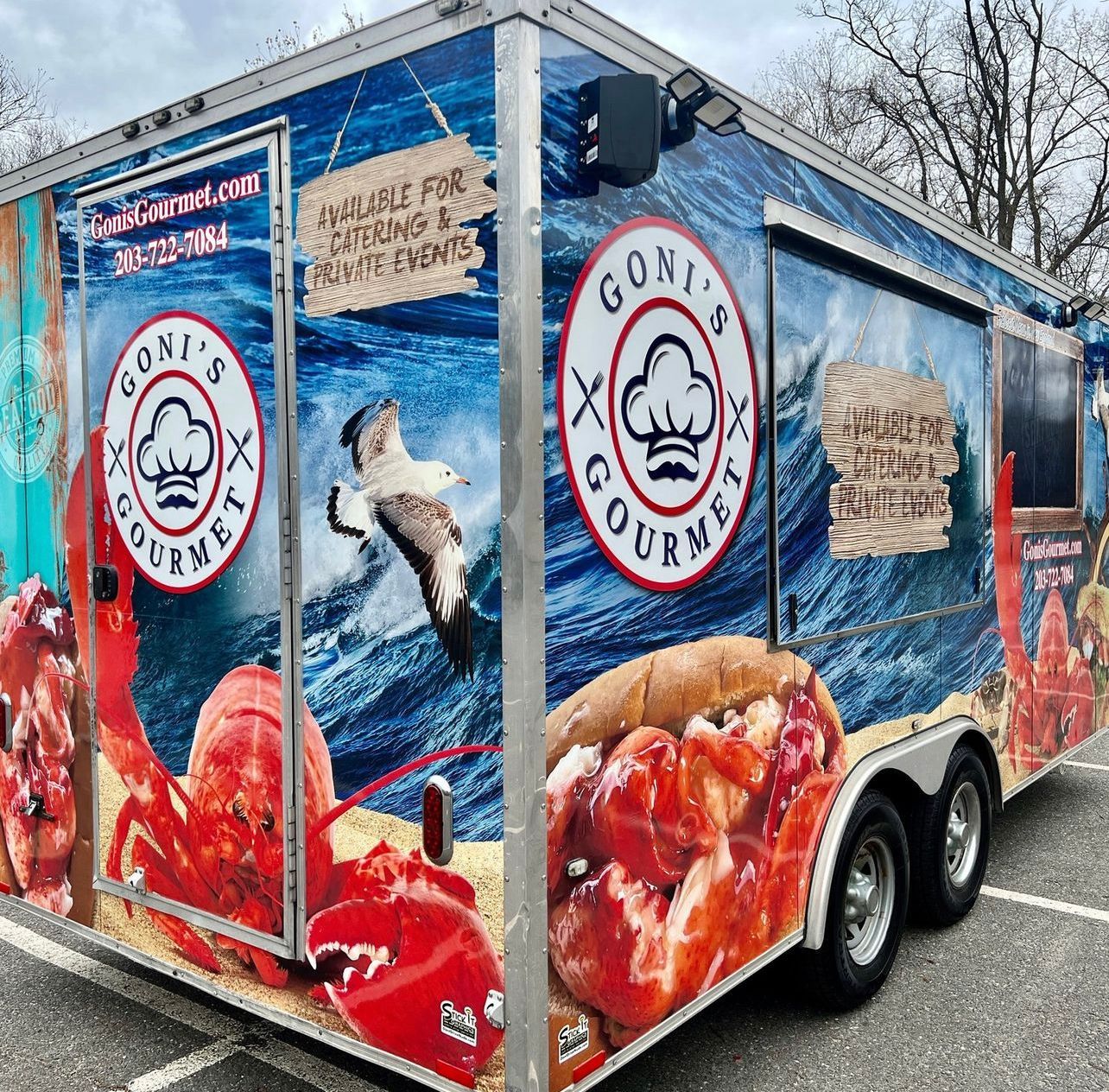 Gino’s Courtyard seafood trailer with blue wrap, lobster graphics, and logo on a snowy street