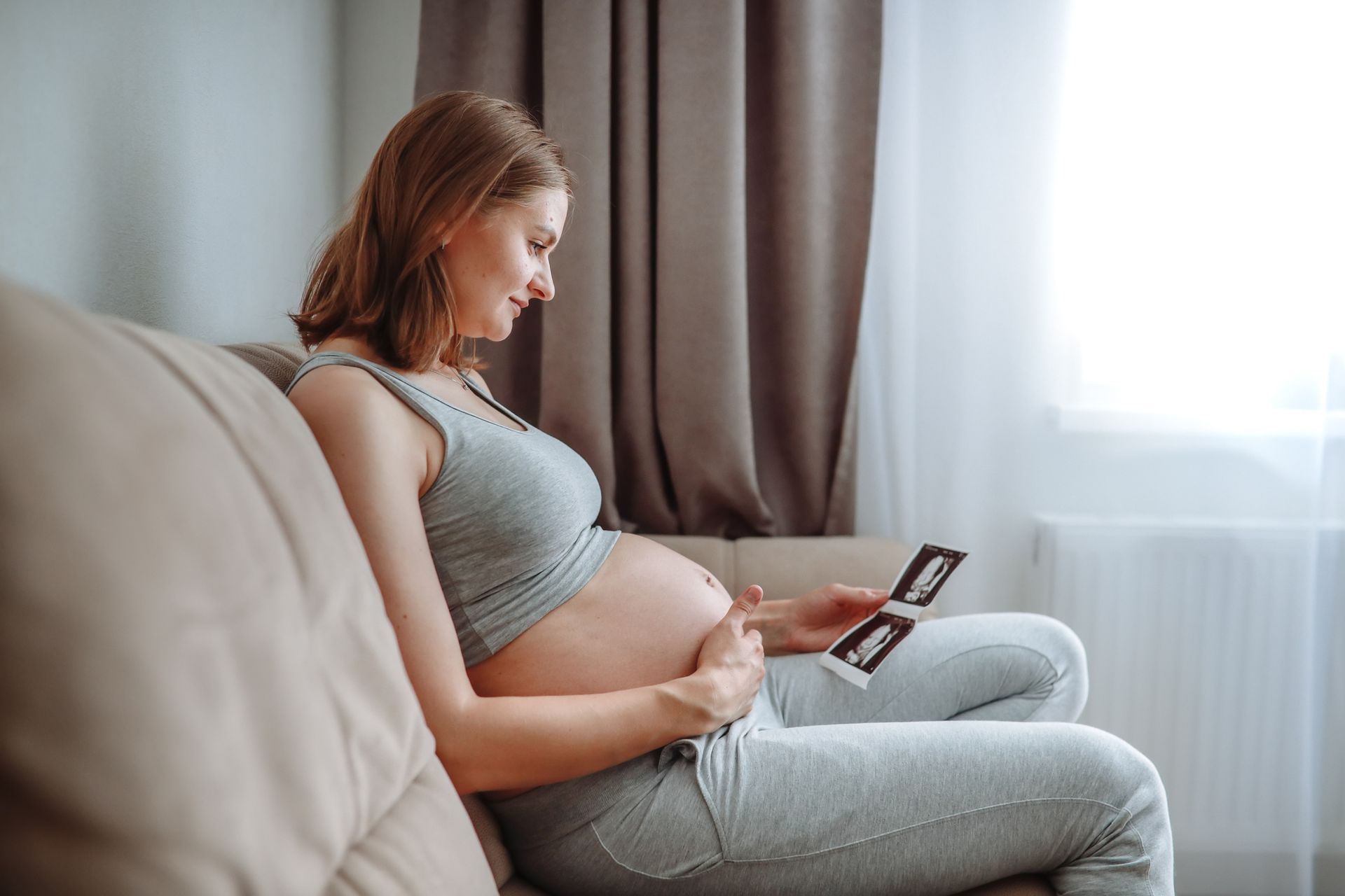 Pregnant Woman Sitting on A Couch — Gowen, MI — RiverSong Midwifery