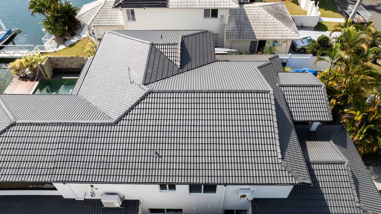 Two men are standing on top of a tiled roof.