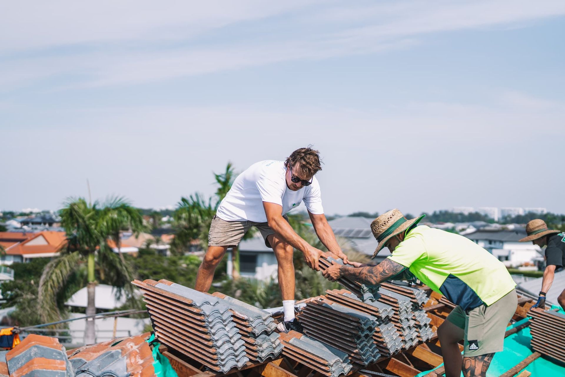 Two men are standing on top of a pile of bricks on a roof.