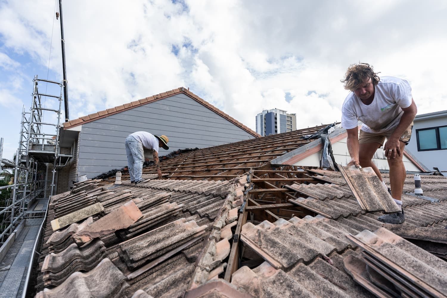 Two men are working on the roof of a house.
