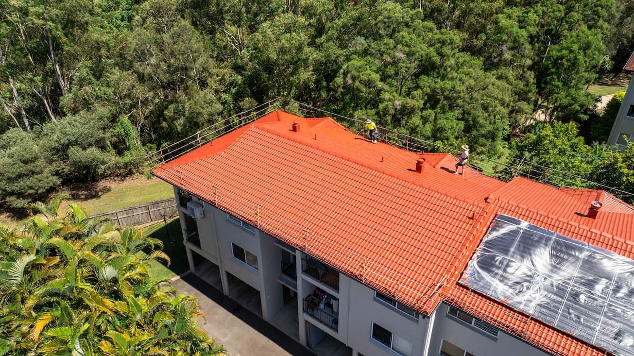 An aerial view of a house with a red tiled roof and solar panels on the roof.