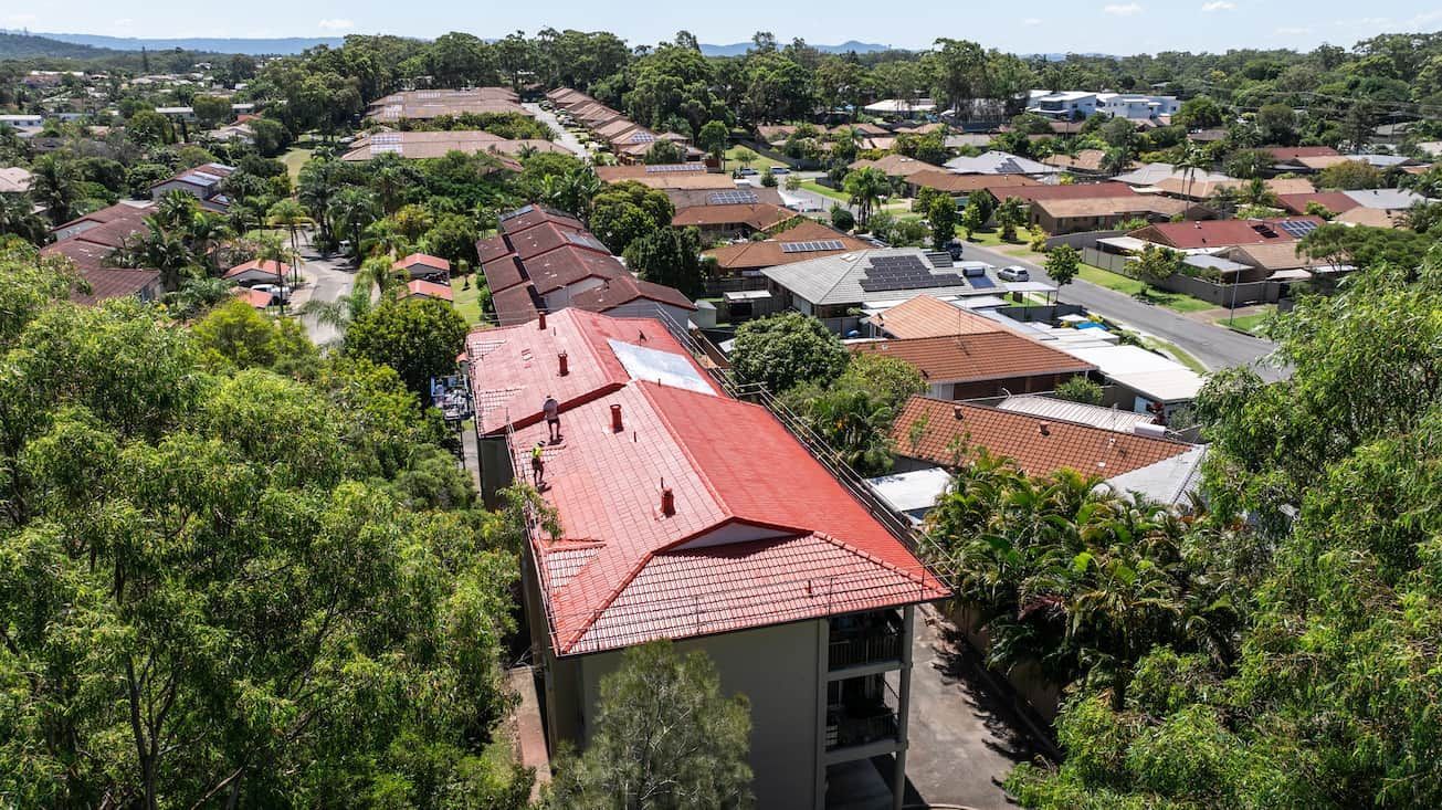 An aerial view of a residential area with a red roof surrounded by trees.