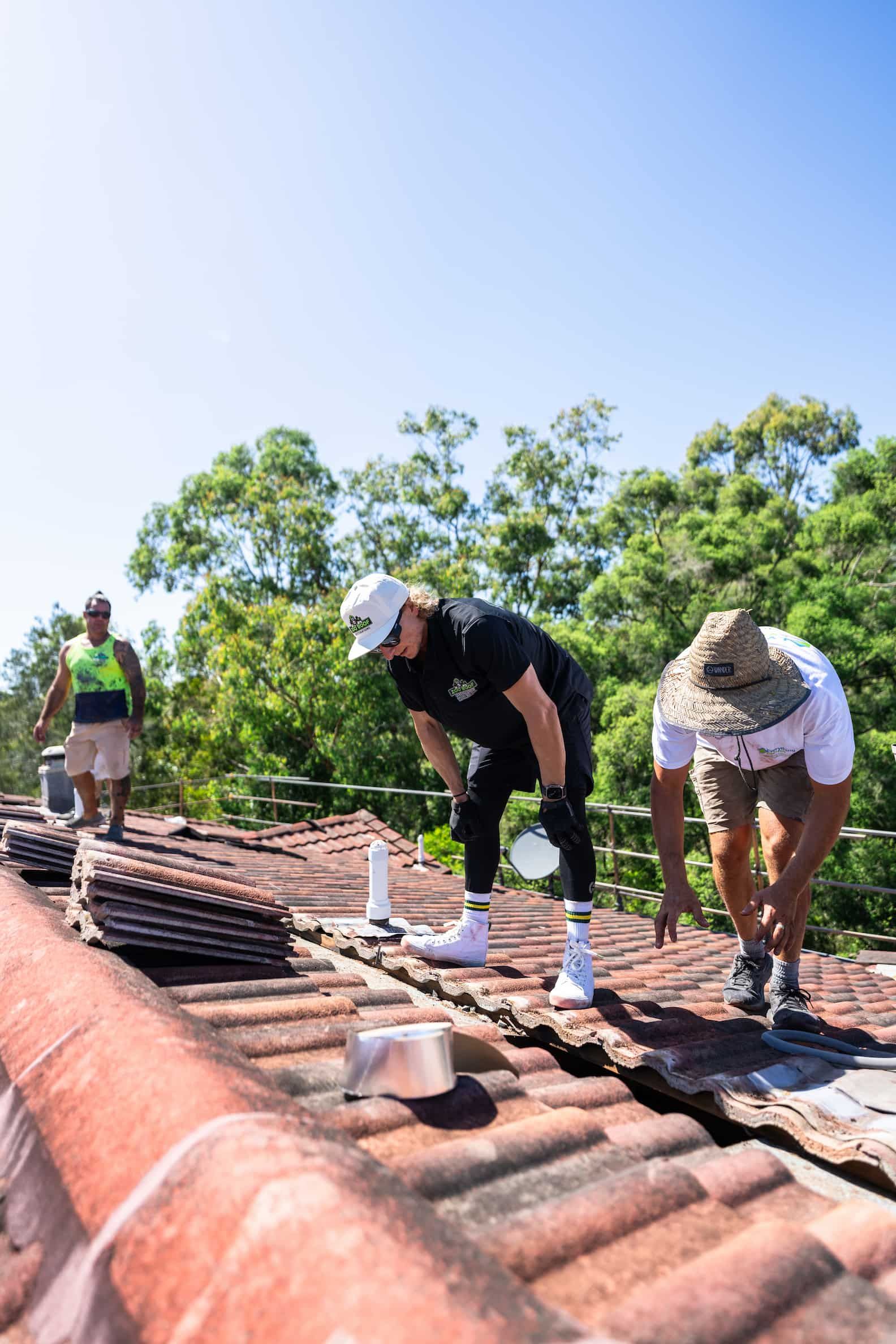 A group of men are working on a tiled roof.