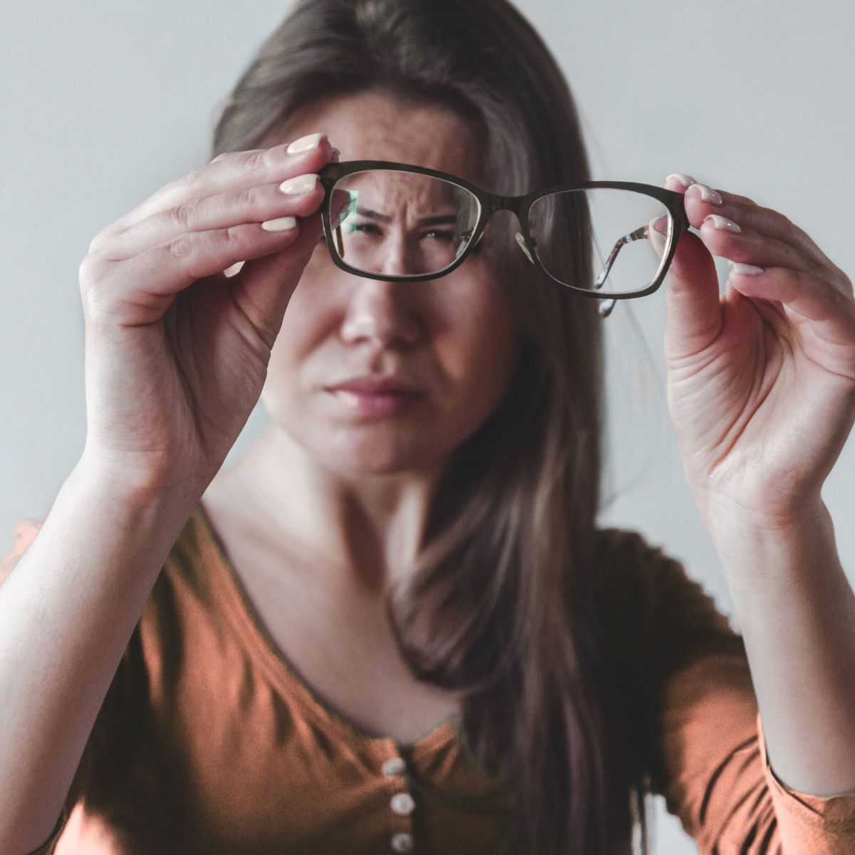 Woman looking through glasses due to blurry vision in one eye