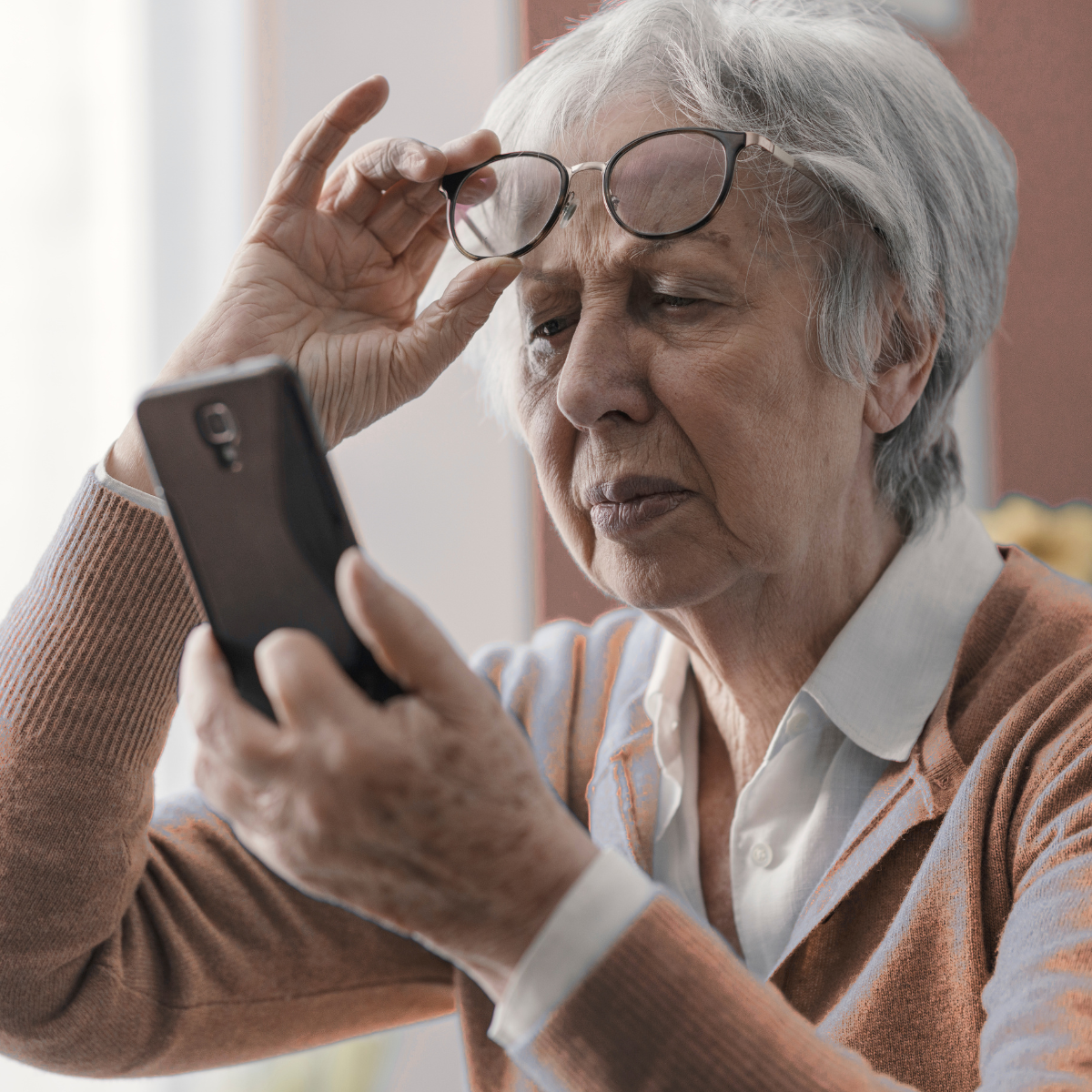 Woman struggling to see phone representing eye problems in elderly