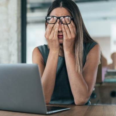 A woman is rubbing her eyes at computer screen. Why do eyes feel tired after a full night's sleep?