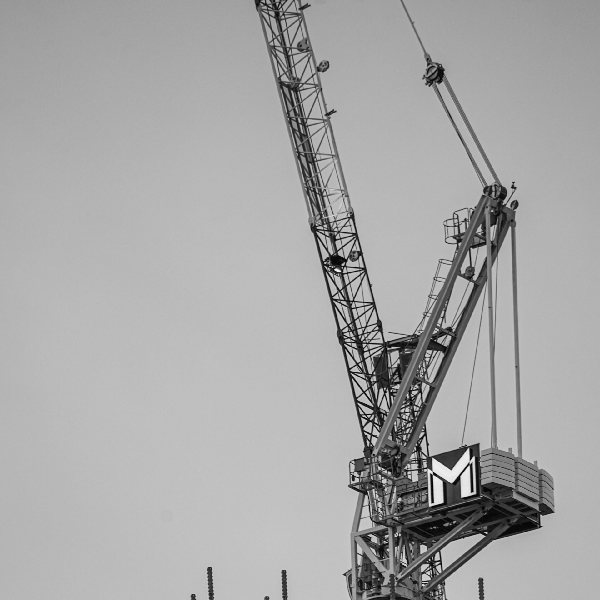 Black and white photo of a construction crane against a cloudy sky.