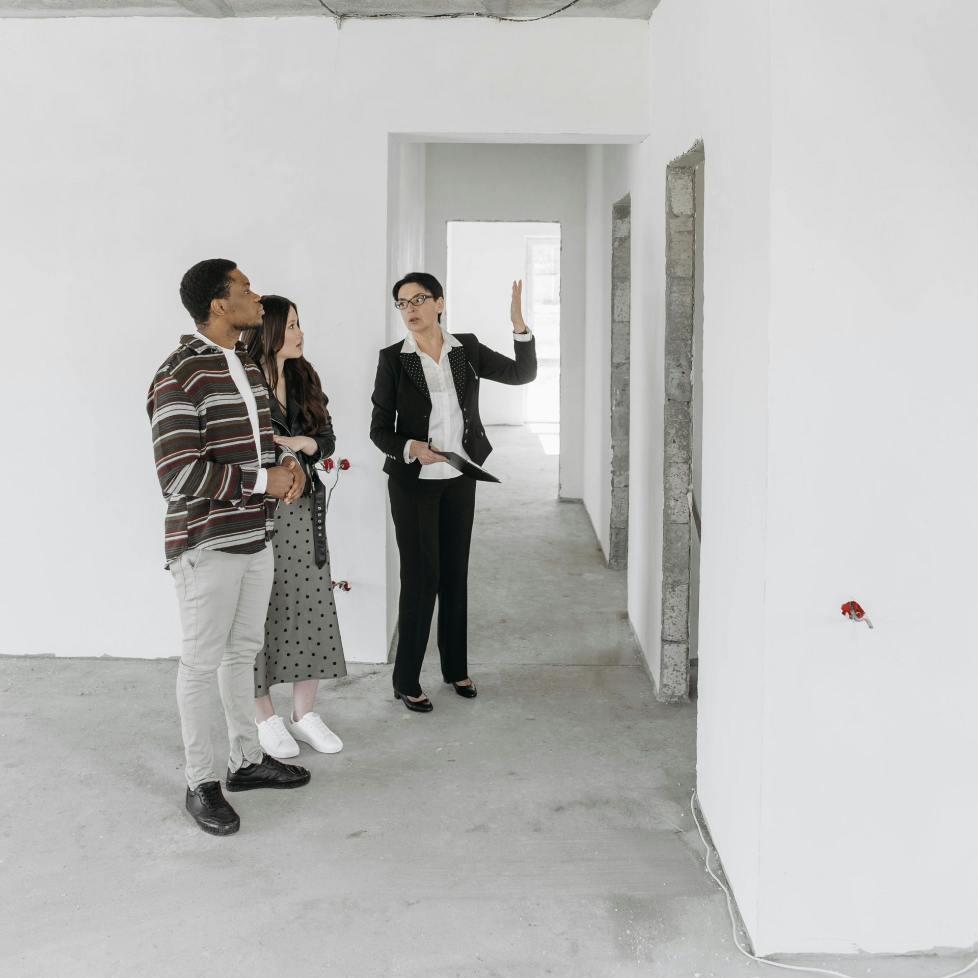 Real estate agent showing a couple a blank apartment with unfinished walls and doorways.
