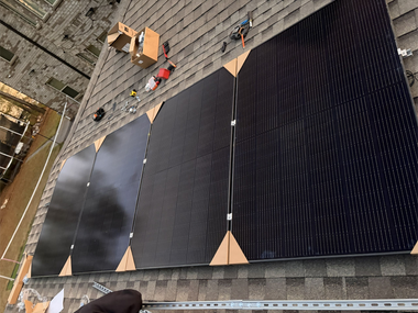 Rooftop with large black solar panels and workers on a brick building roof