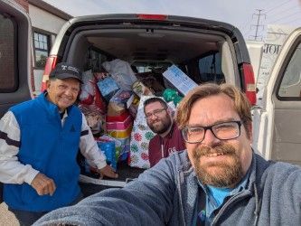 Three men with gifts in van, likely for donation.