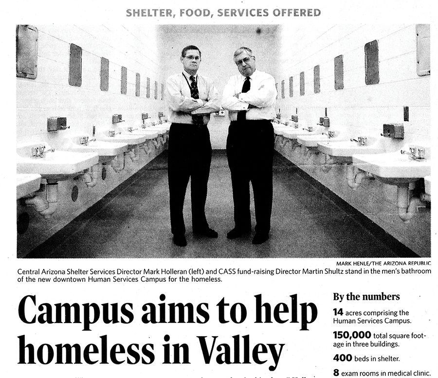 Two men standing in a row of sinks, promoting a homeless services campus. Text reads