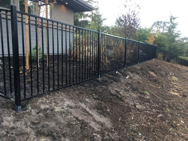 A black metal fence is sitting on top of a dirt hill.