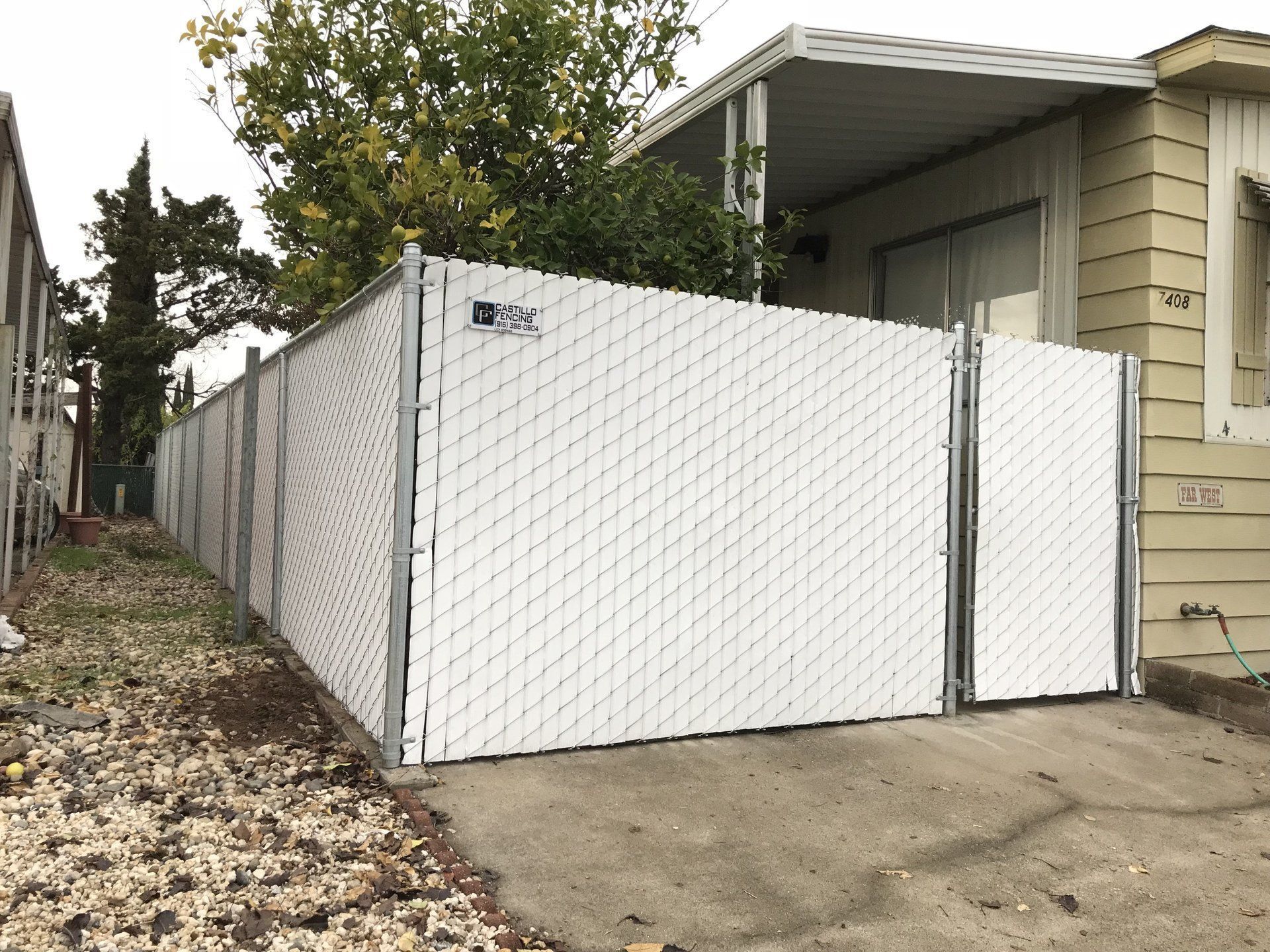 A white chain link fence is surrounding a mobile home