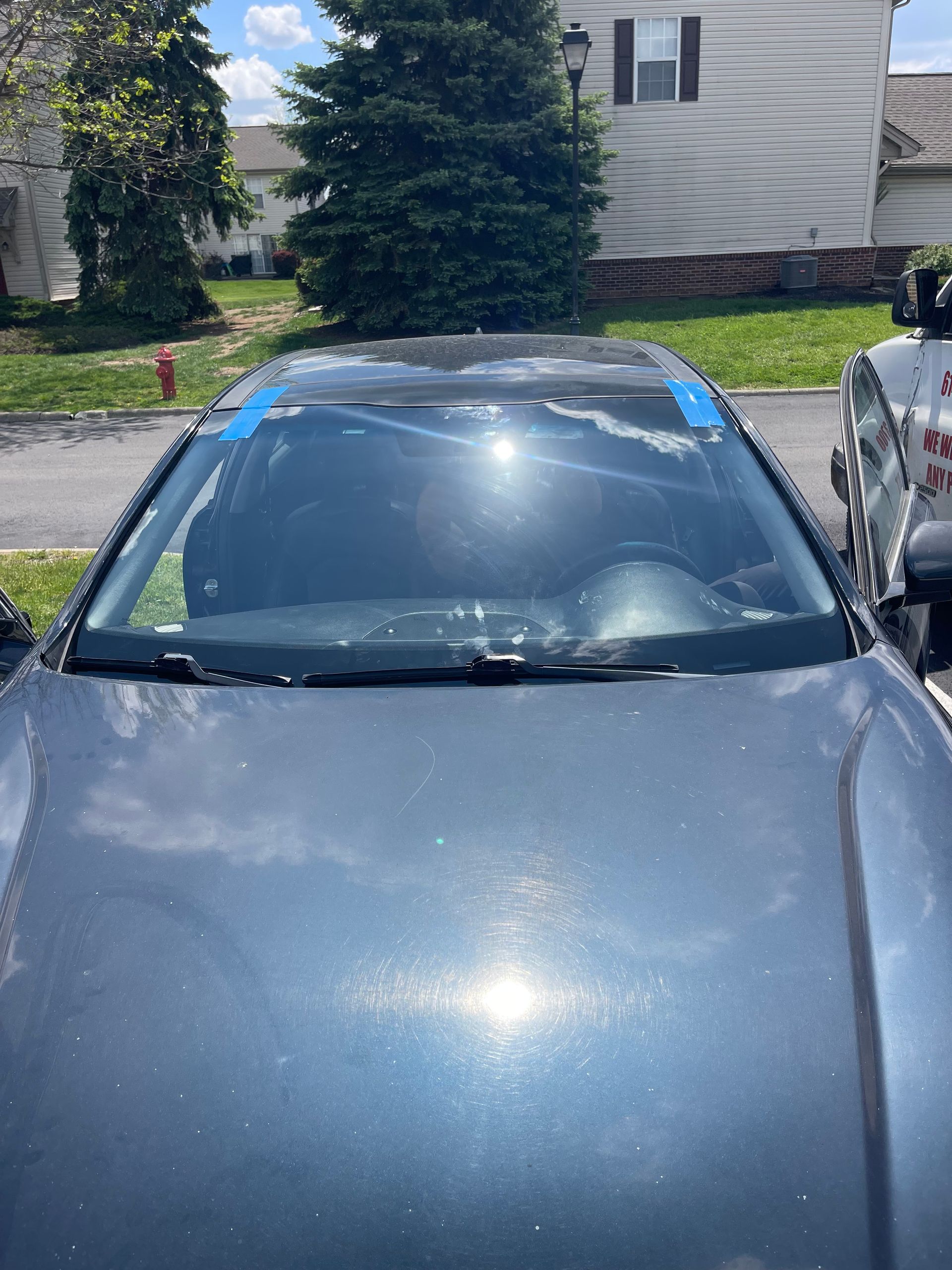 Front view of a gray car parked in a driveway under bright sunlight