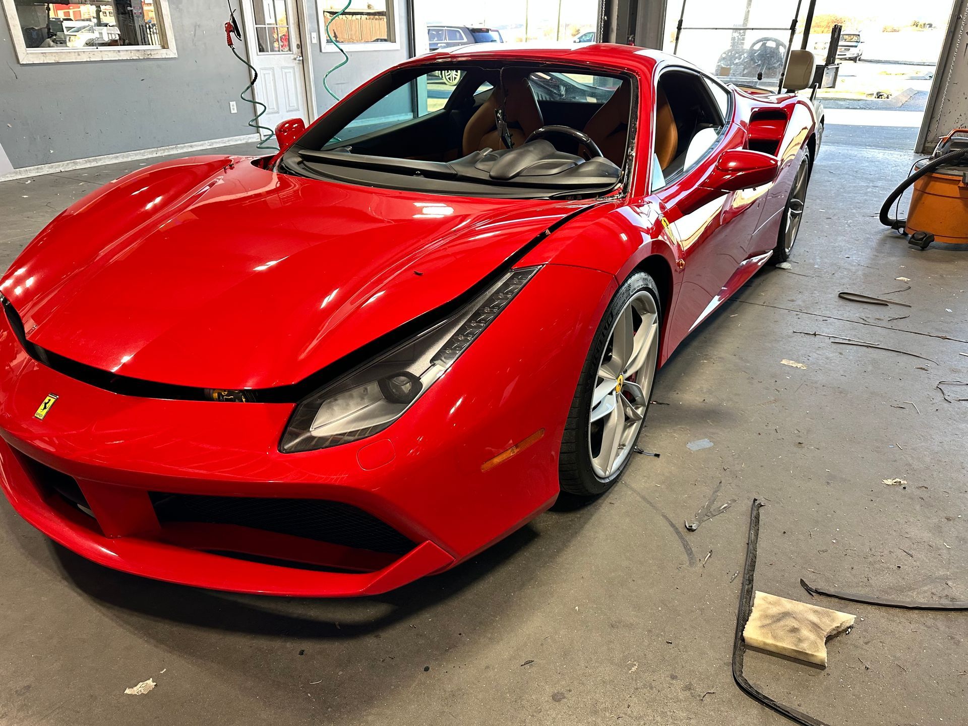 Hands in black gloves repair a windshield with a red tool.