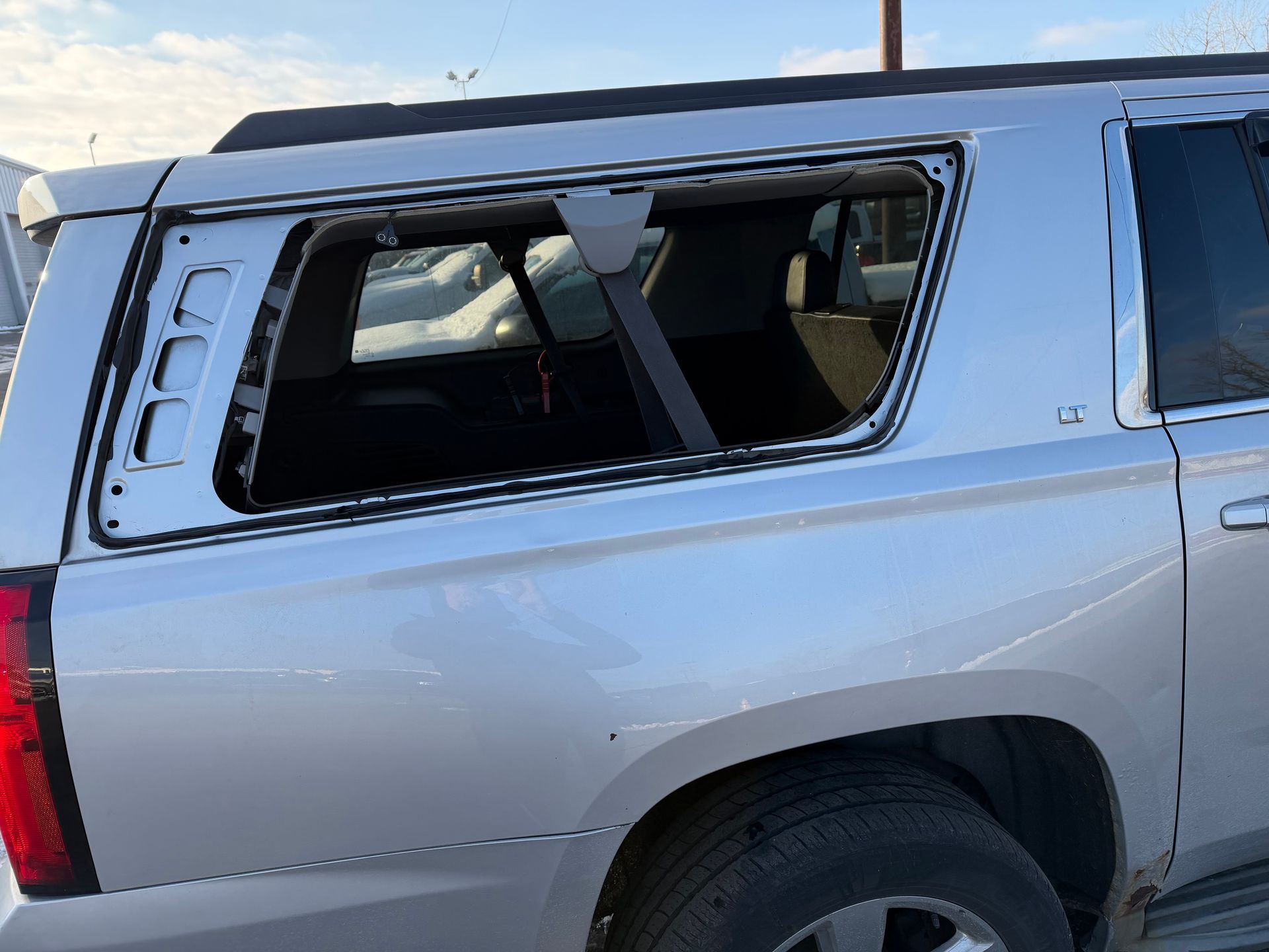 Silver SUV with shattered rear side window and visible damage